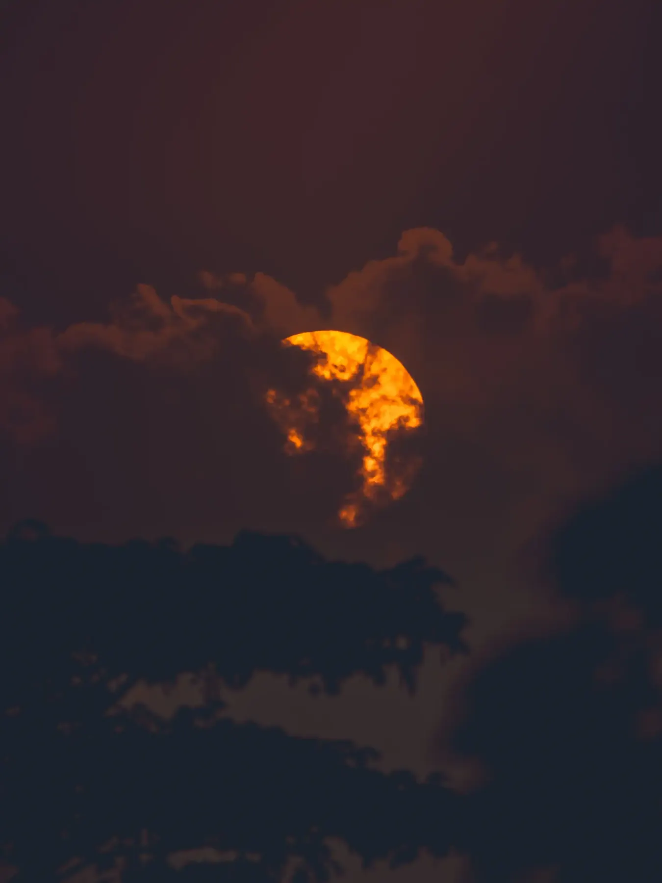The moon partly hidden behind glowing clouds
