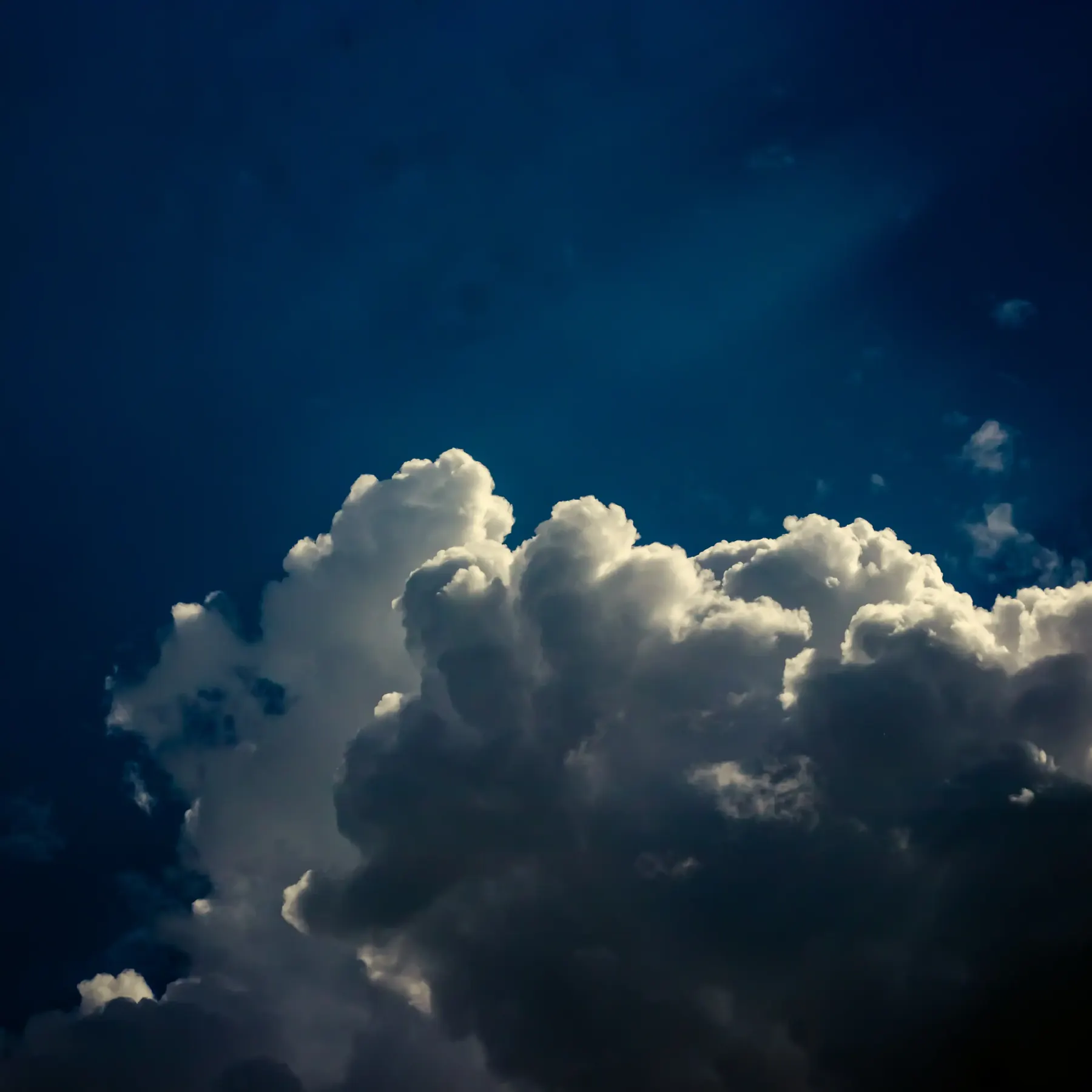 A tall white cloud billowing against a blue sky
