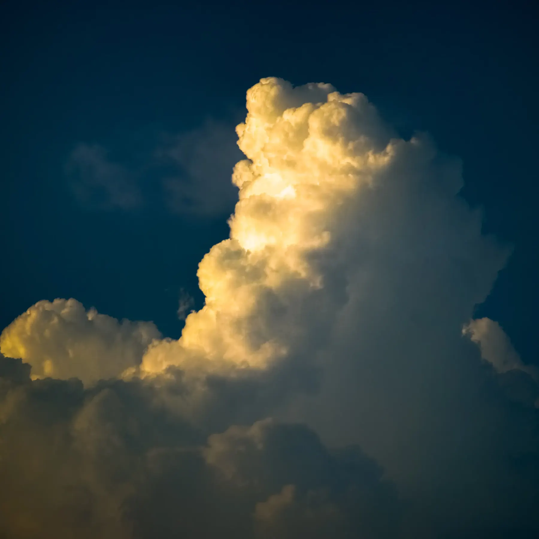 A tall cumulus cloud lit gold against a blue sky