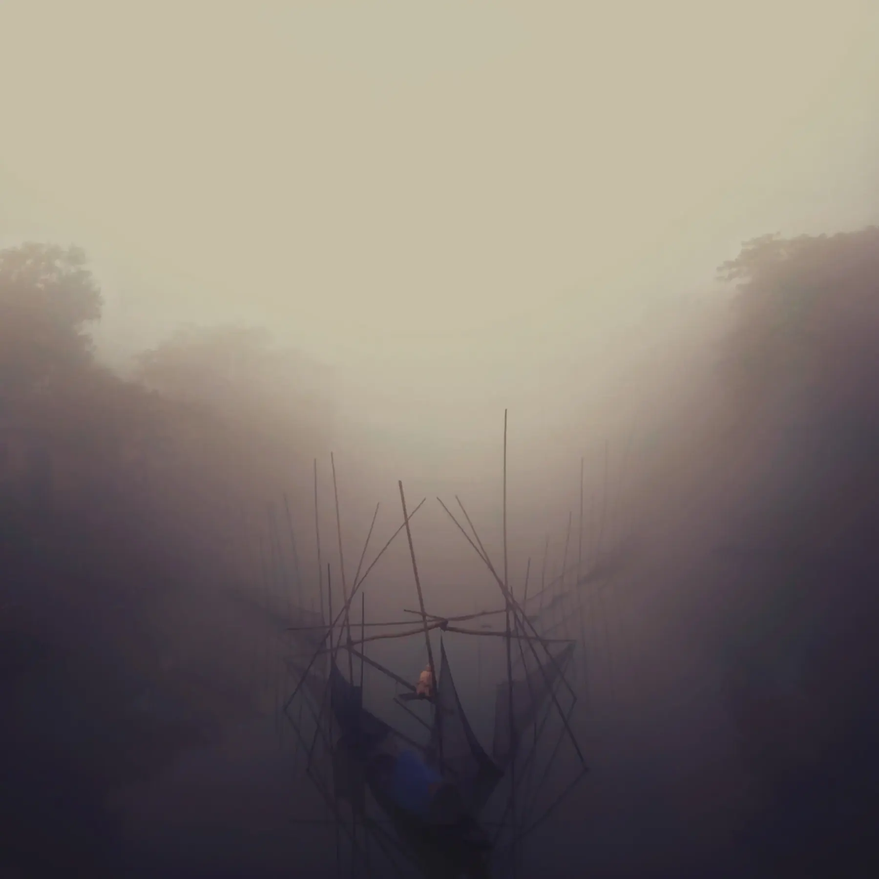 A wooden boat emerging from thick river fog