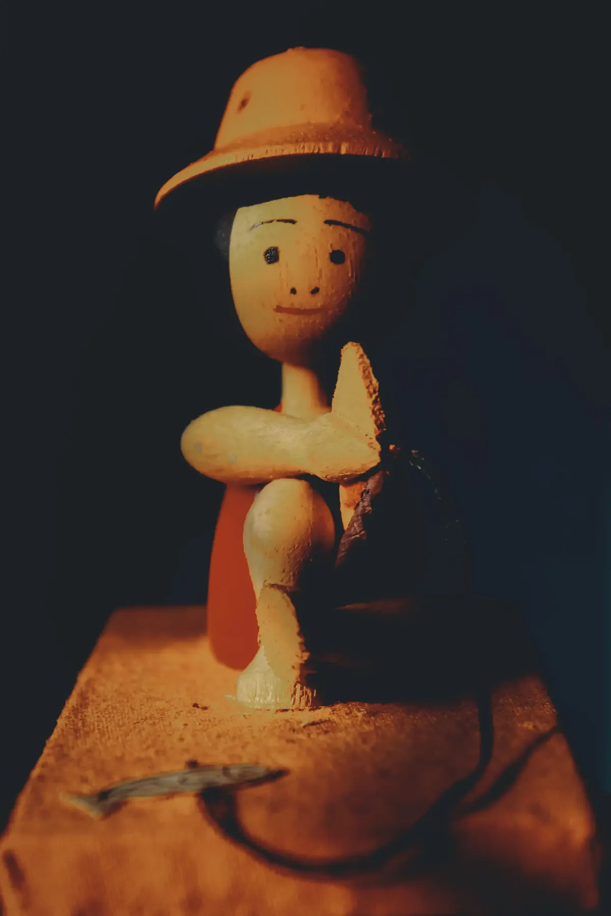 A hatted wooden toy figure seated on a stool